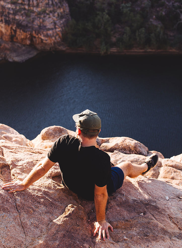 man standing on a mountain cliff during a MAT session, reflecting deeply