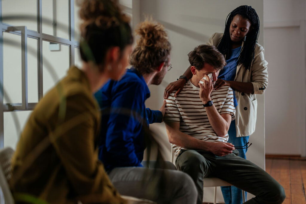 a man cries and is comforted during a group therapy session about what to expect